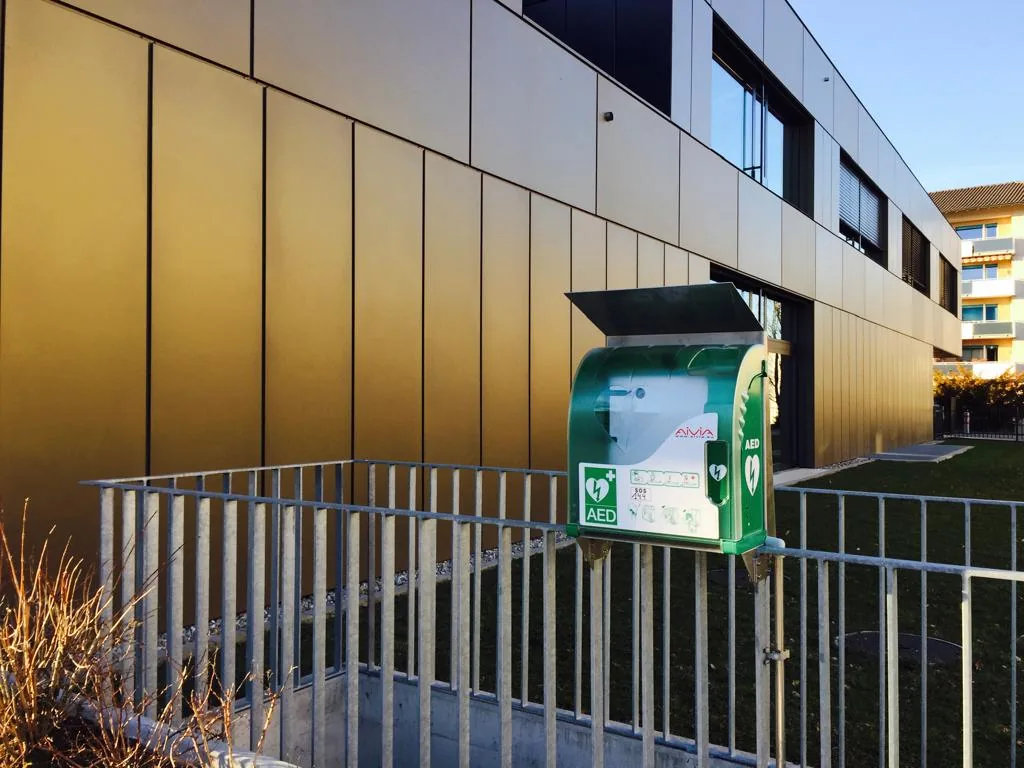 Défibrillateur en armoire extérieure le long d'un bâtiment de l'École hôtelière.